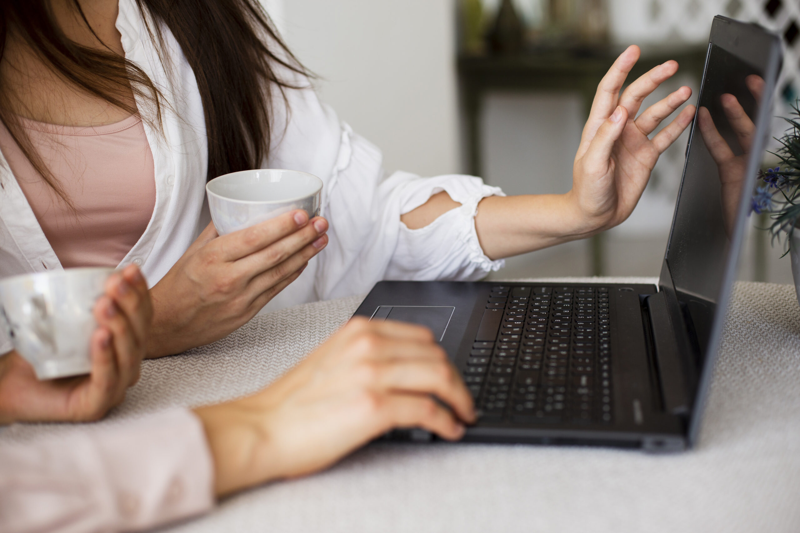 Symbolbild Online-Austausch. Zwei Frauen sitzen vor dem PC und führen ein Online-Meeting