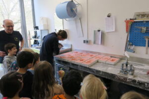 Kleine Gesundheitshandwerker beobachten Sarah Frank beim Ausgießen der Handabdrücke mit Gips.